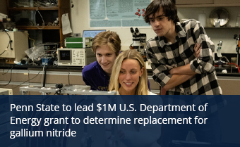 Three students lean over lab equipment